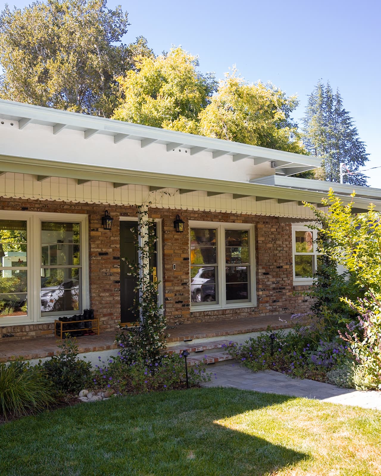 Covered brick front porch with climbing star jasmine at the remodeled home's entry
